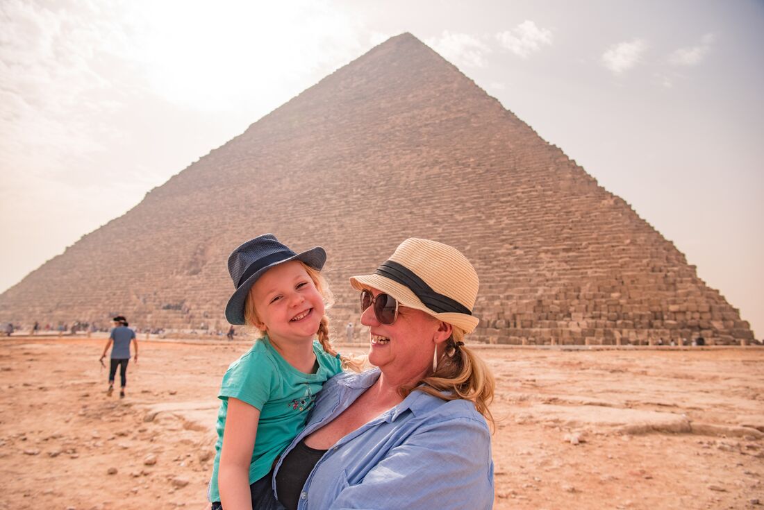Mother and daughter smile together in front of one of the Great Pyramids of Giza in Cairo