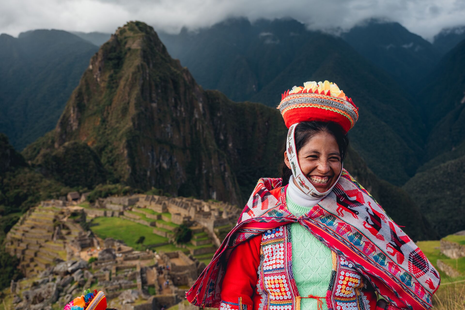 Woman from Sacred Valley smiling in front of Machu Picchu, Peru