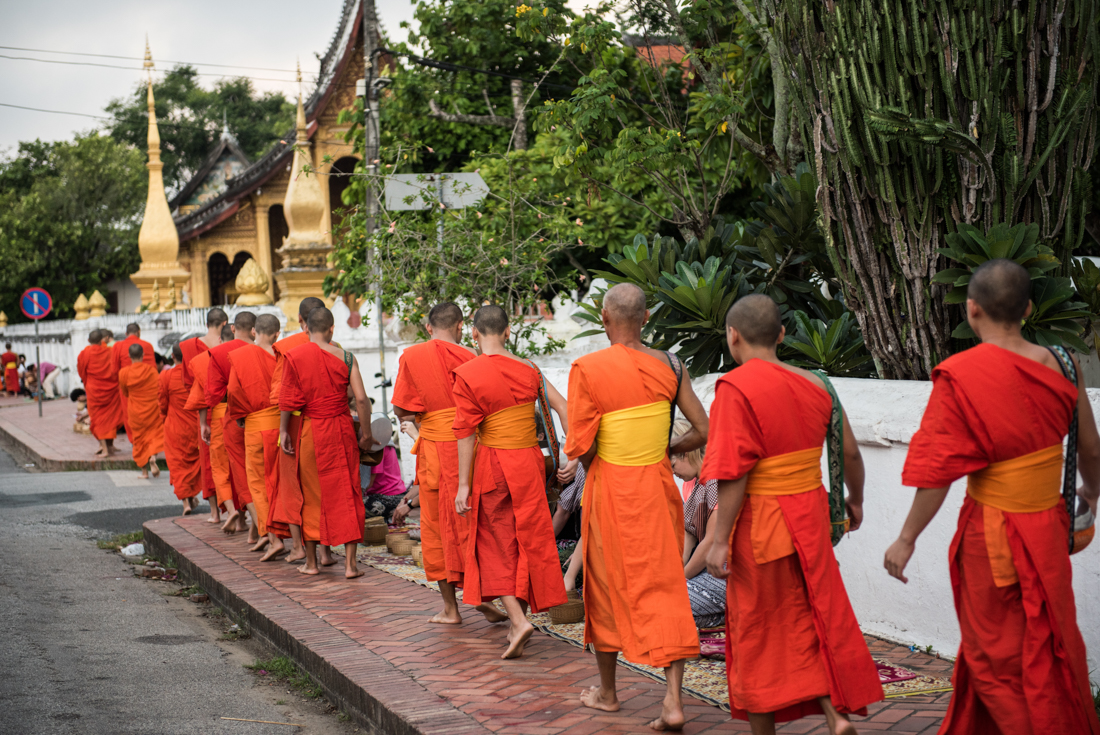 Buddhist monks walk through Luang Prabang with special buckets for alms in Laos