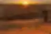 Group of travellers stand on a dune looking out at the sunset in Erg Chigaga