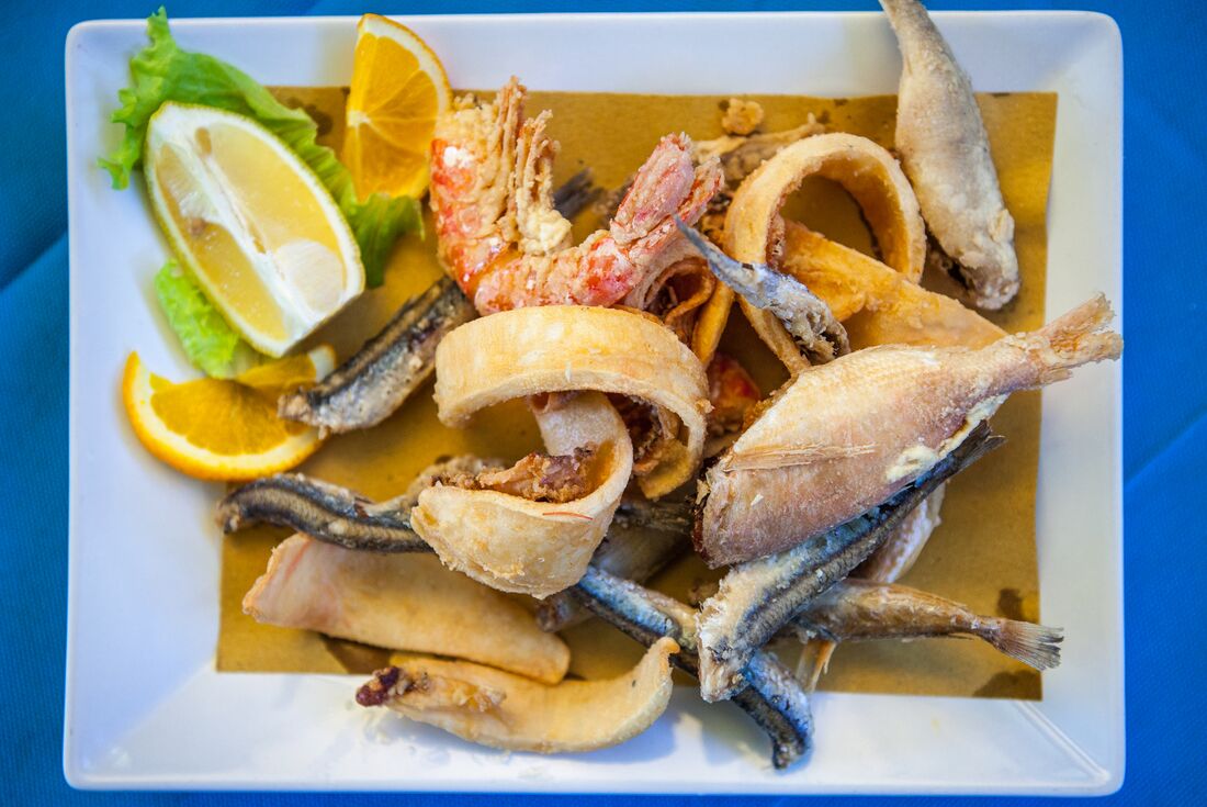 Fresh Amalfi seafood plate of fish, crustaceans and fried onions with lemon on the side