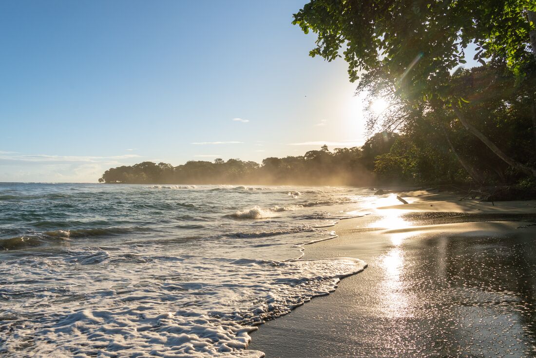 The beautiful warm waters of Puerto Viejo washing onto rainforest lined beaches in Costa Rica