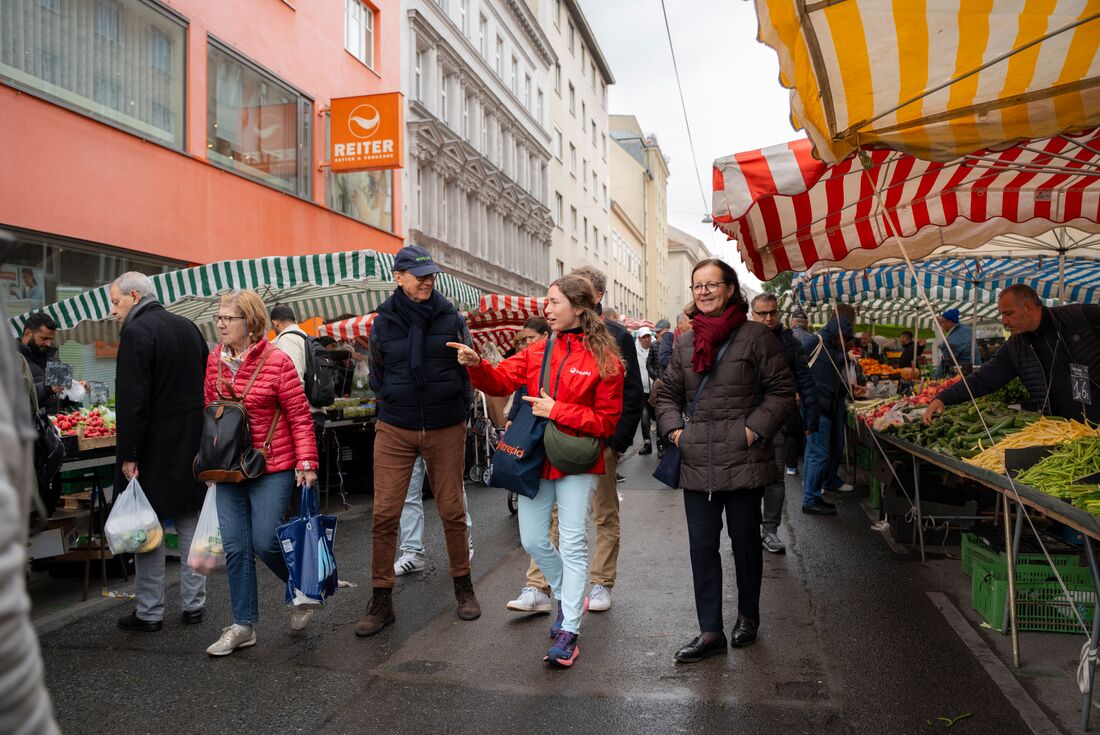 Leader walking with travellers in a market in Vienna, Austria 