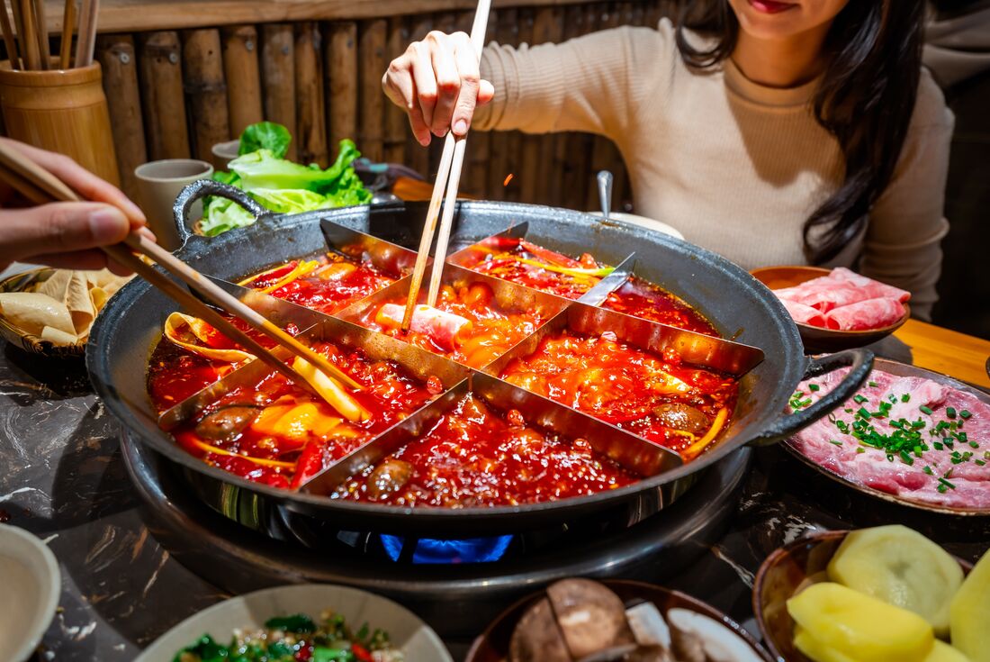Travellers reach into and dine on a classic Chongqing hotpot with a 9 part divider in Hunan