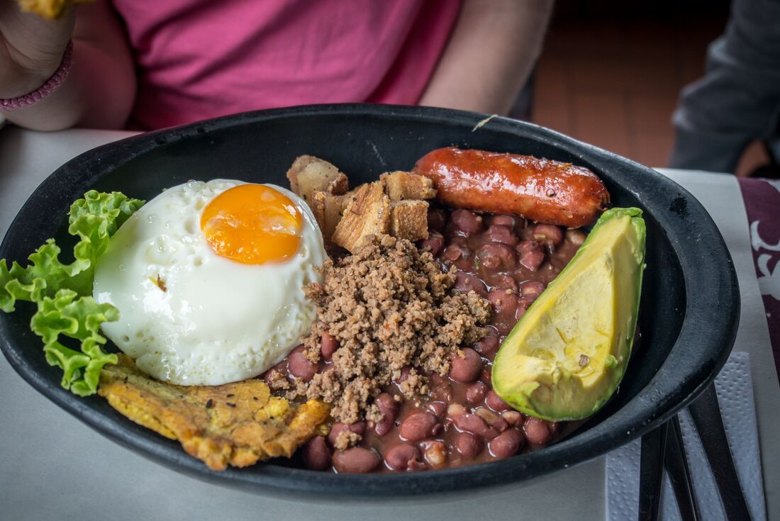A plate of bandeau Paisa, a traditional dish of Colombia consisting of mince beef, chorizo sausage, fried egg, red beans and plantains 
