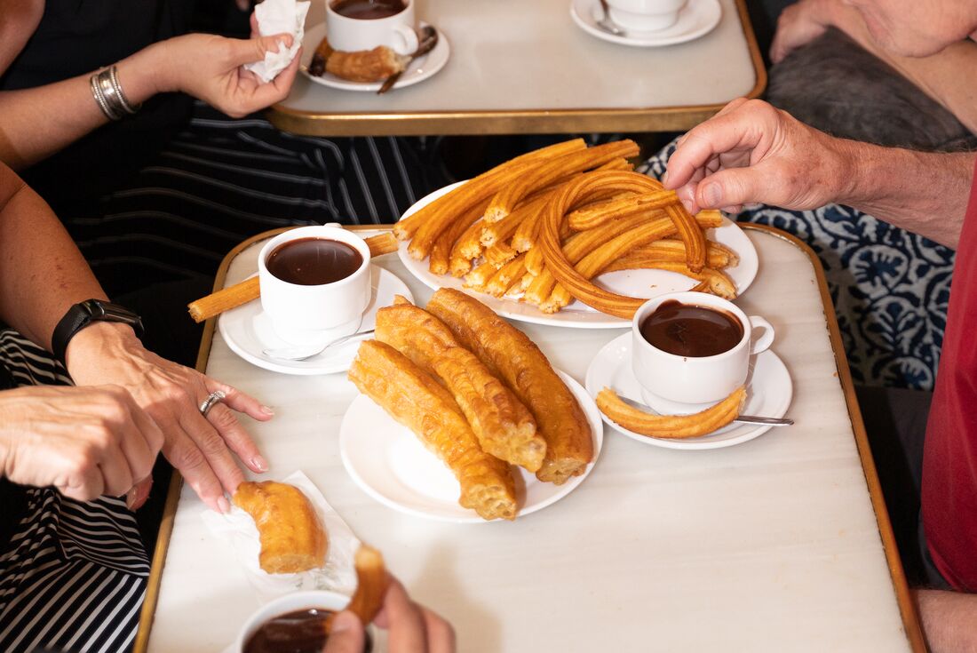 Plates of fresh churros and warm, dark chocolate for dipping in a churreria in southern Spain