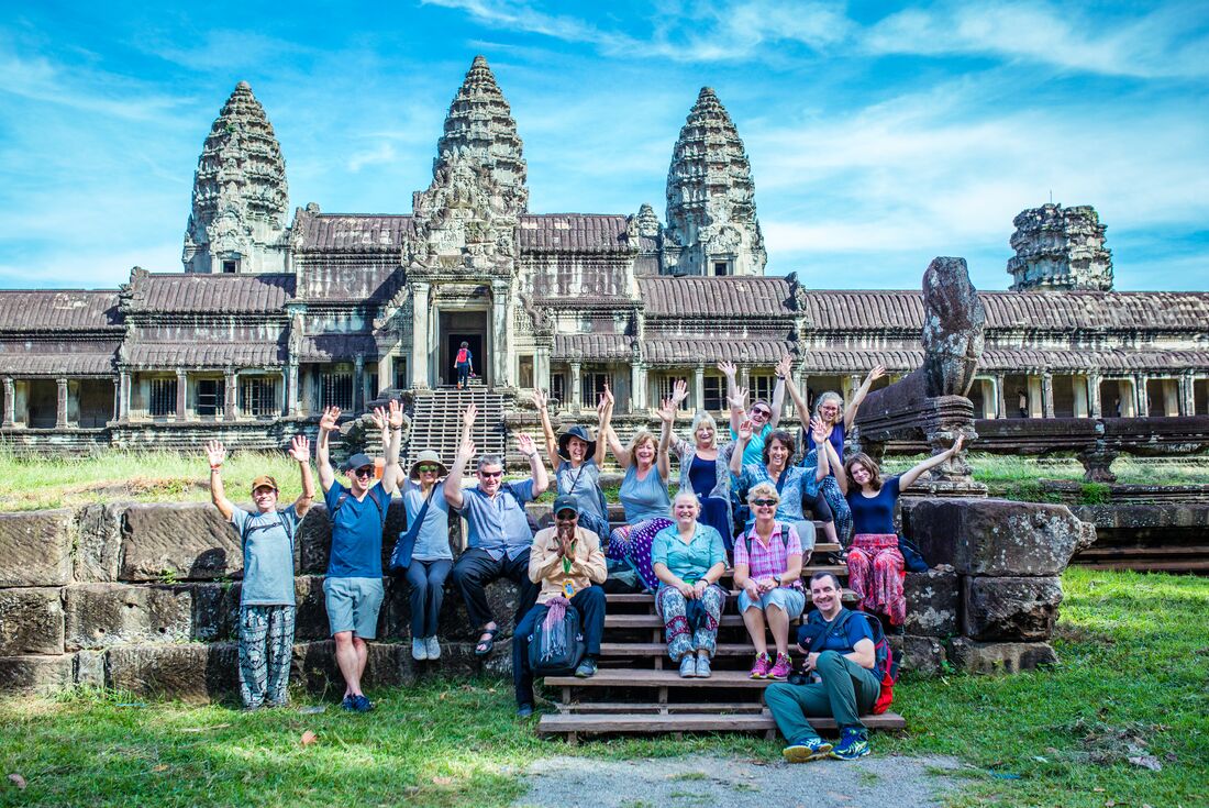 Group of travellers pose on the steps of Angkor Wat in northern Cambodia