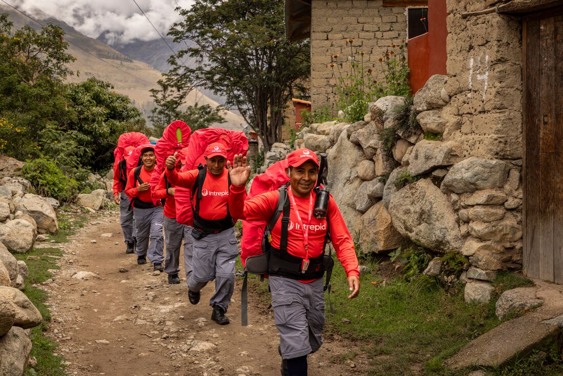 Intrepid porters wave and smile at the camera as they begin hiking the Inca trail