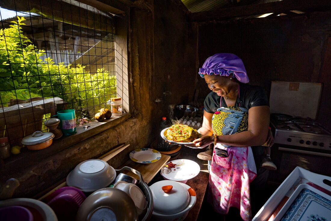 Smiling local woman looking at her home-cooked meal, Laiti, Ghana