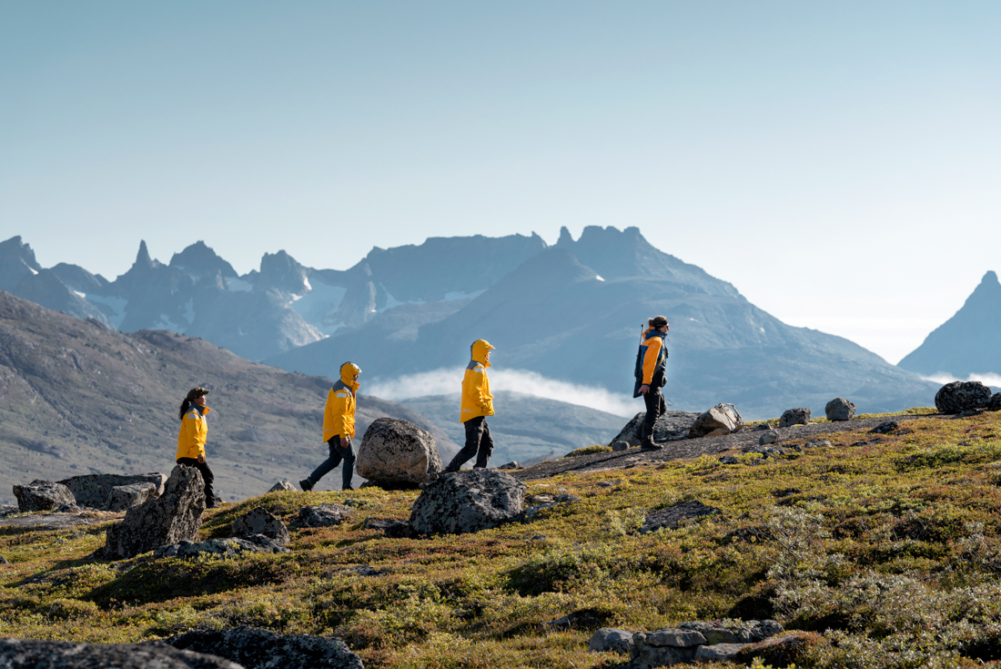 Travellers hiking along a ridge near a fjord in Greenland