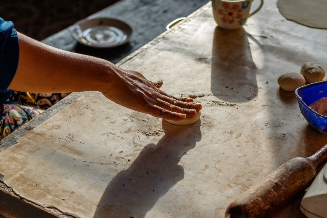 Instructor begins to roll a ball of dough on a sunlit surface during a momo dumpling making class in Nepal