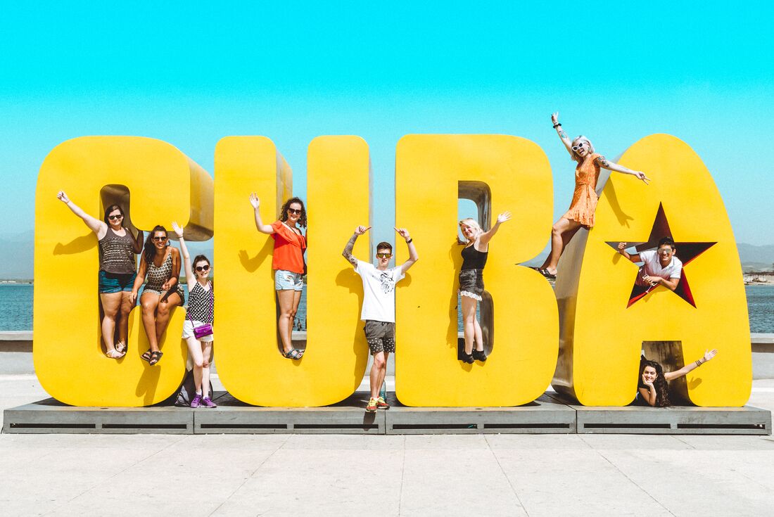 Intrepid travellers spread out across a large text sculpture of Cuba on the Havana waterfront