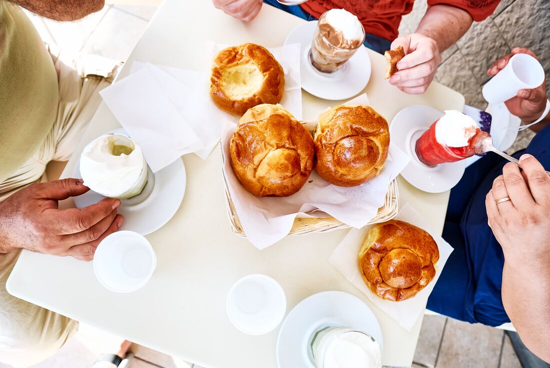Topdown view of travellers eating granita iced desserts and brioche buns on Italy southern coast
