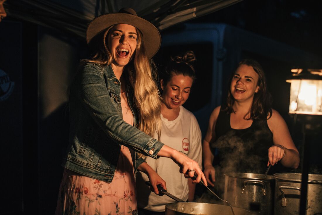 Intrepid travellers laugh and smile cooking dinner togetther at a campground in the USA