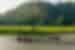 Wide shot of travellers and leader being guided on rowboats in the wide river valley of Van Long Nature Reserve