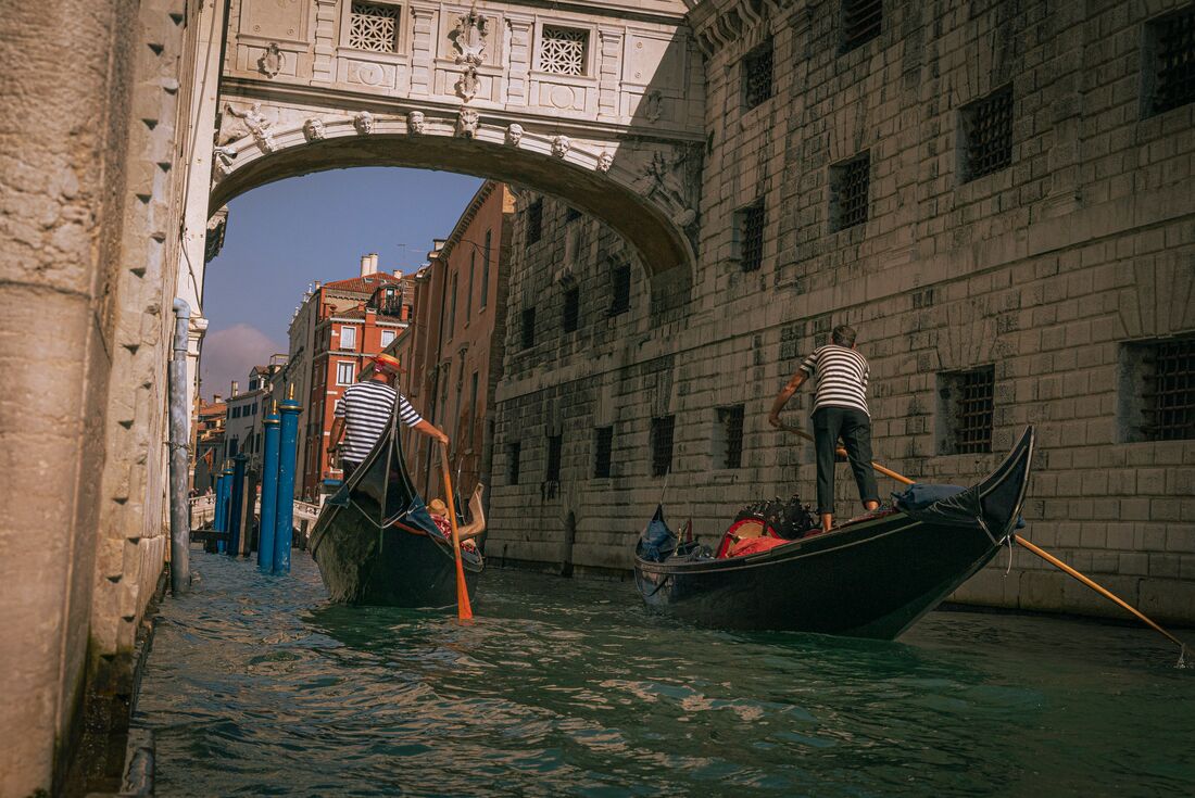 Two gondolas in a canal going under a bridge in Venice, Italy