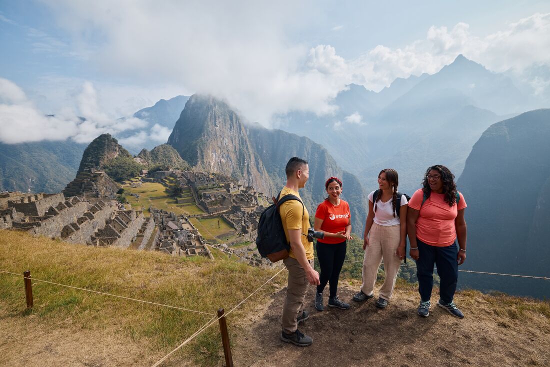 Intrepid travellers talk and laught together at the Machu Picchu lookout in Peru