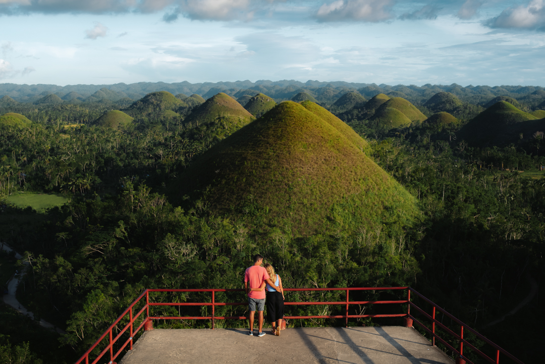 Intrepid traveller couple on viewing platform marvelling at the Chocolate HIlls in Bohol Philippines