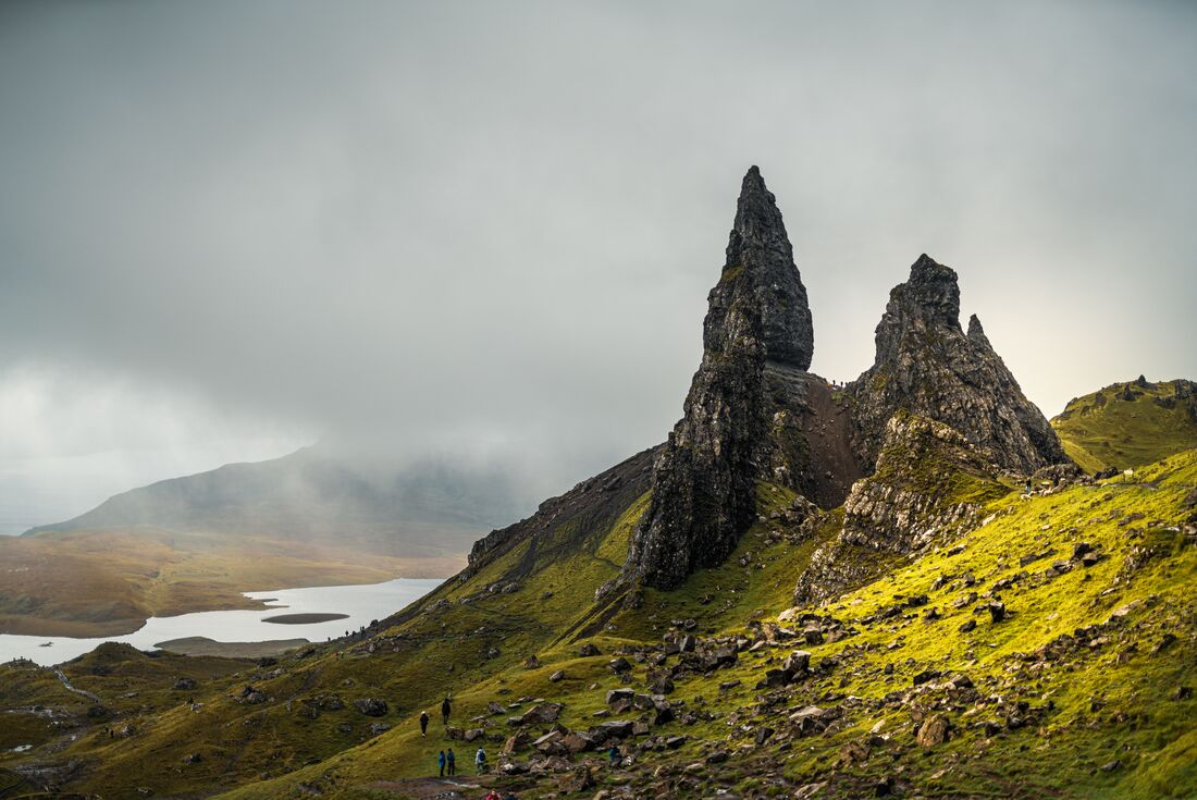 Travellers look up at the towering Old Man of Storr on the Isle of Skye in Scotland