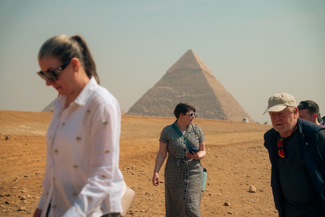 Travellers in Cairo with The Great Pyramids of Giza in view behind them, Egypt