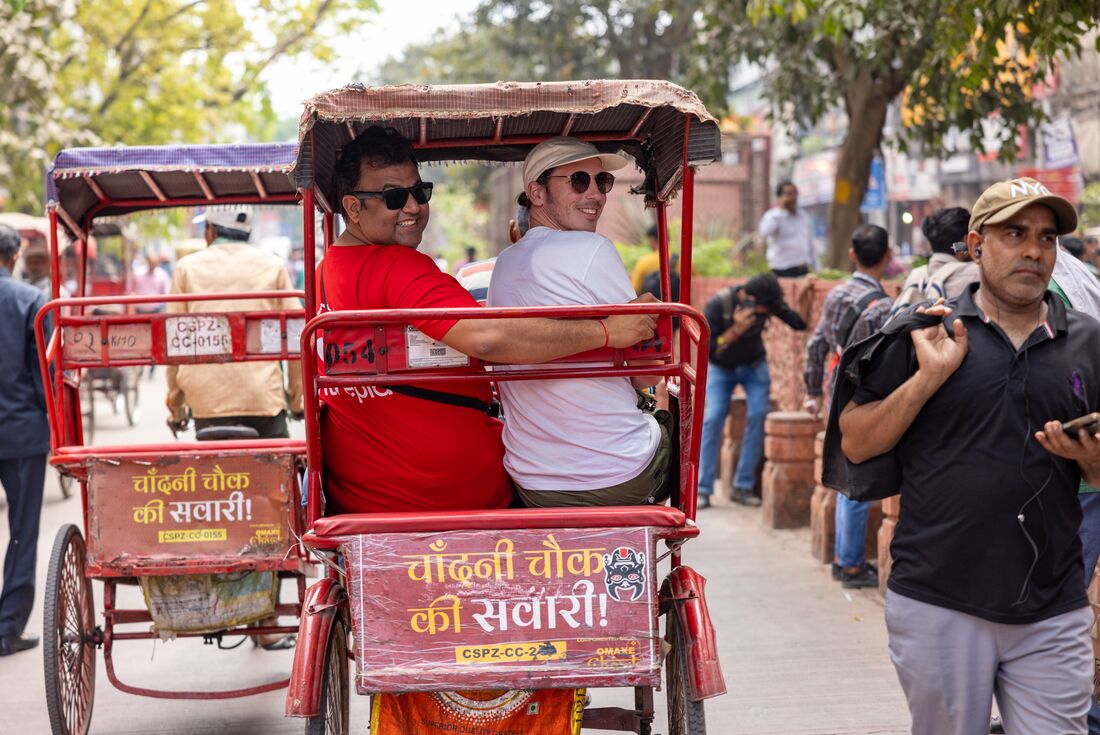Intrepid leader and traveller smile back on authentic rickshaw ride in New Delhi streets in Rajasthan India