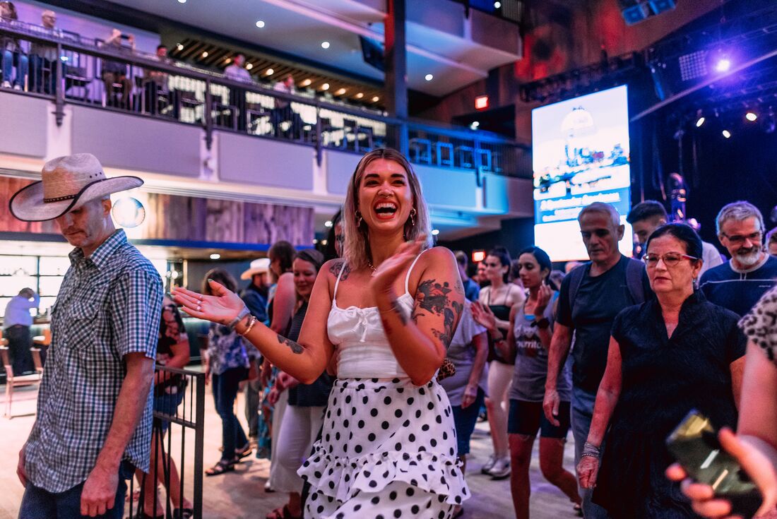 Travellers dances and claps happily at a bar in nashville during a dancing lesson