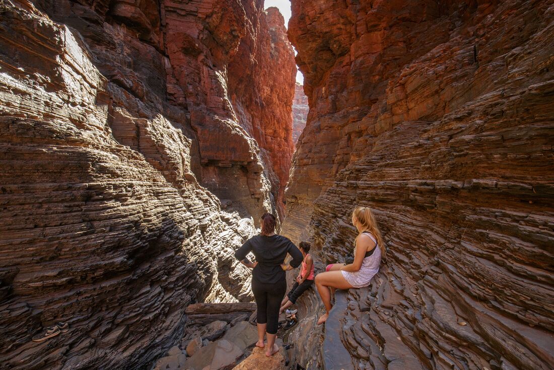 Travellers look as light shines through the openings of Karijini Gorge in Western Australia