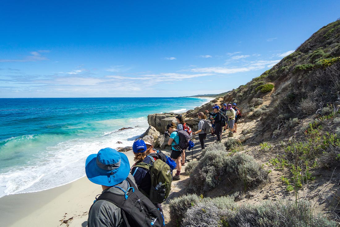Travellers walking along beach on the Cape to Cape track, Australia