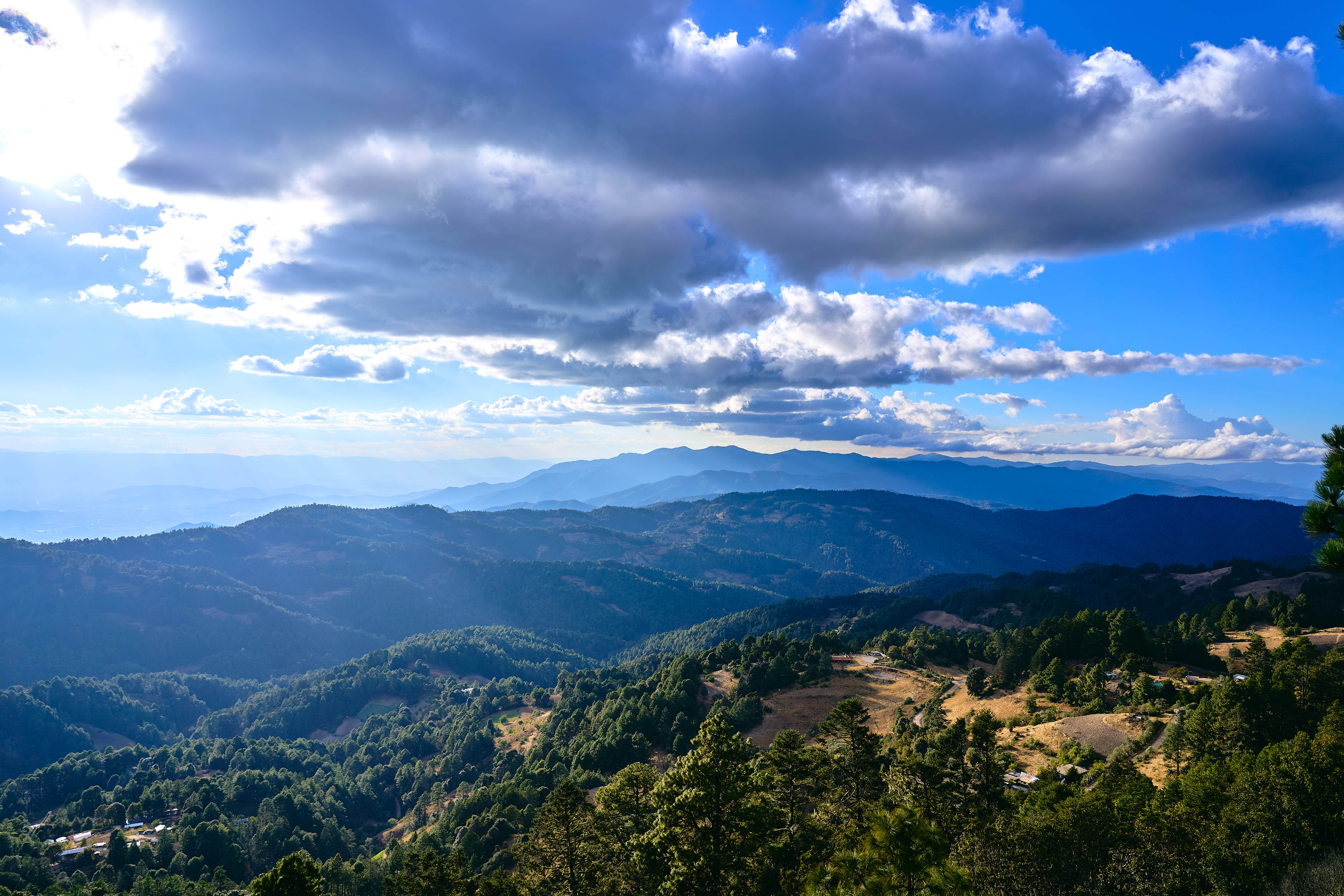 A photo from the top of the Sierra Norte range in Mexico, looking back over a green valley.