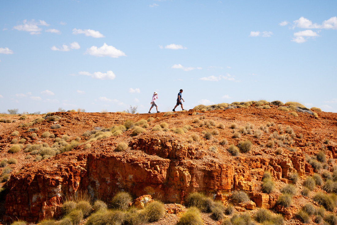 Travellers walking a high orange ridgeline in the Kimberley Western Australia