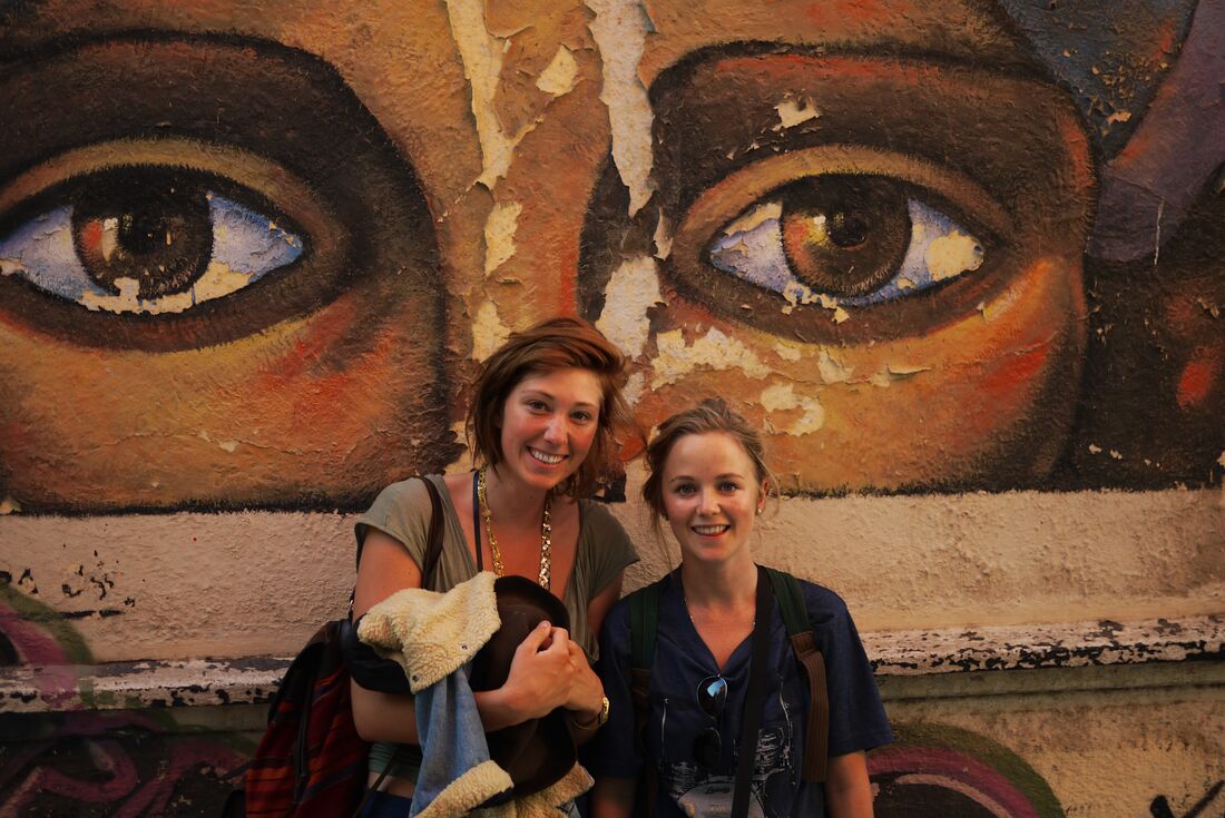 Travellers pose in front of street art of eyes in the streets of Buenos Aires in Argentina