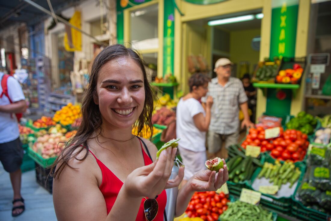Intrepid traveller shows fresh eaten fruit outside a market on Syros in Greece