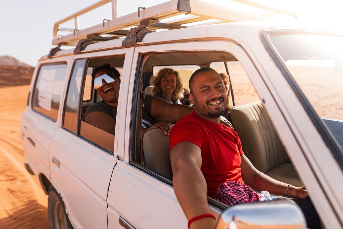 Intrepid leader and travellers smile excitedly at the camera on a 4x4 ride through Wadi Rum