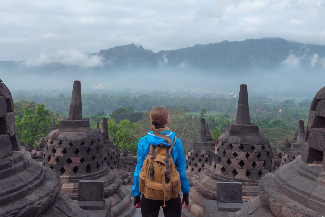 Exploring Borobudur's ancient bell-shaped stupas, looking out over the rainforests of Java