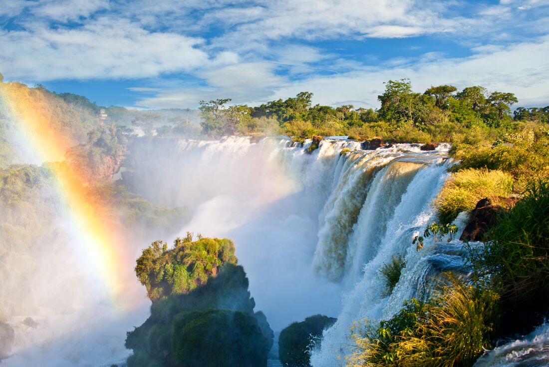 Rainbows arc in the mist from Iguazu Falls seen in Brazil and Argentina